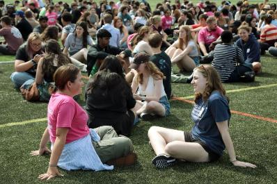 Pack leader and student sitting together on football field playing PUMP