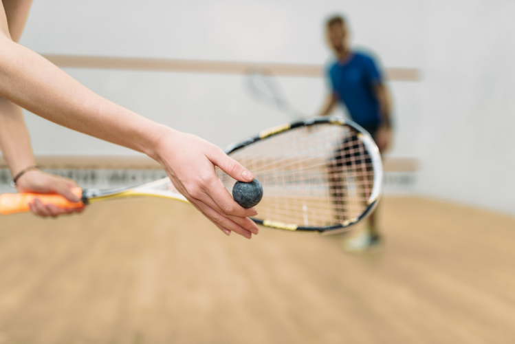 A squash racket and a player in the distance