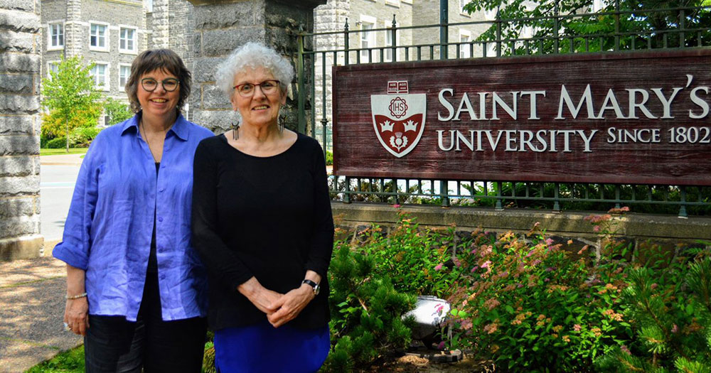Linda MacDonald and Jeanne Sarson beside the Saint Mary's University sign.