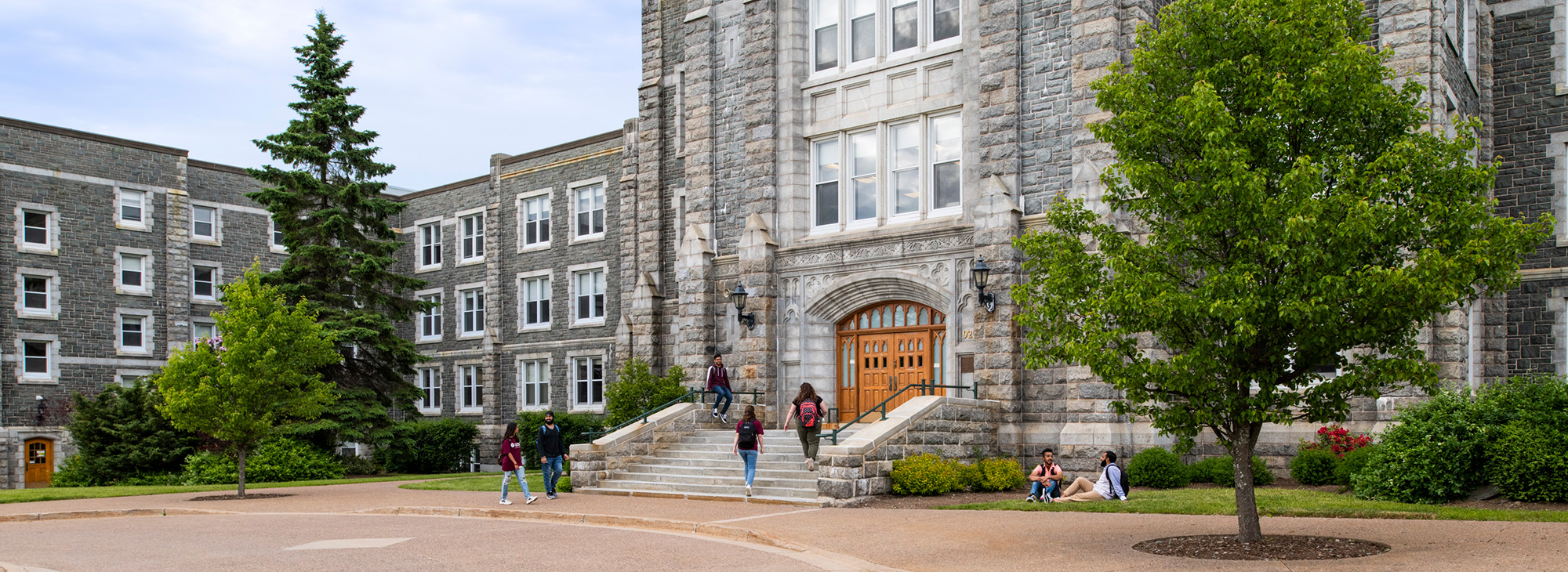 Students waling into McNally while others lounge nearby on the grass.